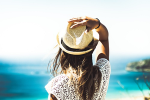 Brunette woman at the beach wearing a straw sun hat